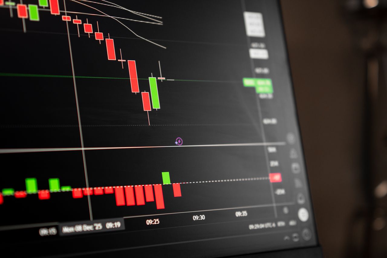 services-img A close-up of a digital screen showing stock market candlestick chart data.