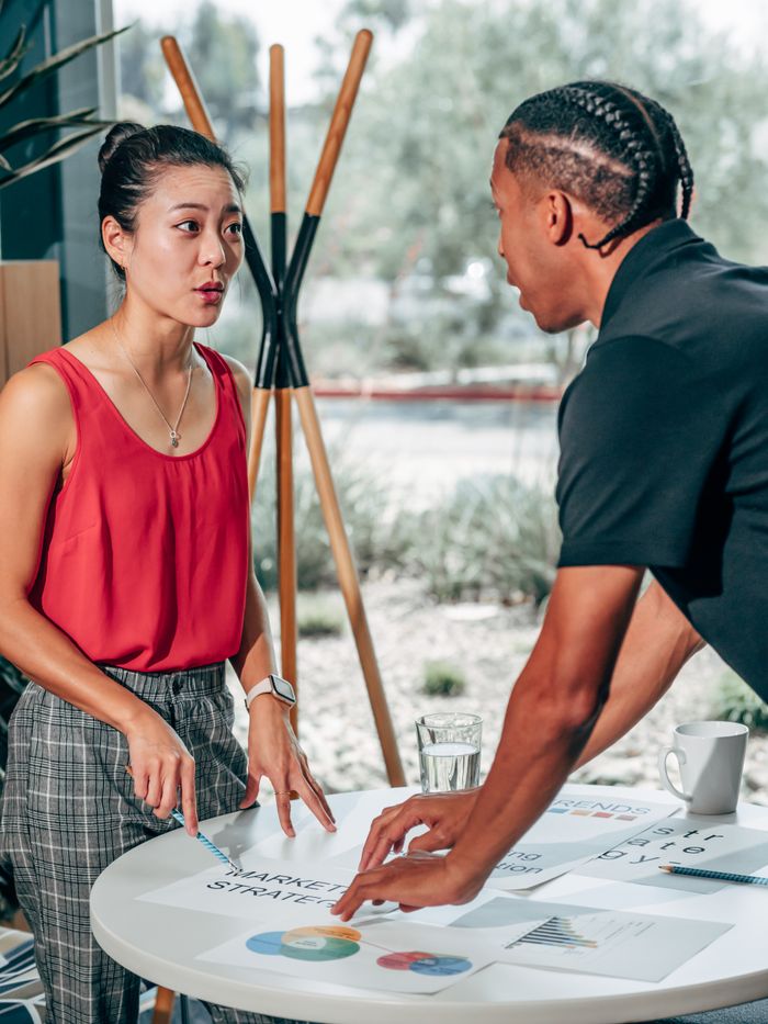 Two professionals engage in a business strategy discussion at an office table.